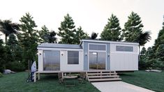 a tiny house on stilts in the middle of a grassy area with picnic table and benches