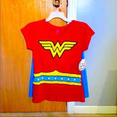 a red t - shirt with wonder woman on it hanging from a door hanger