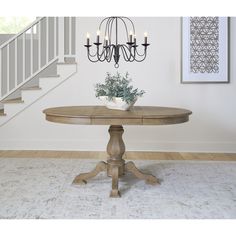 a chandelier hangs from the ceiling above a round dining table with four candles on it