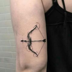 a woman's arm with an arrow and bow tattoo on the left side of her arm