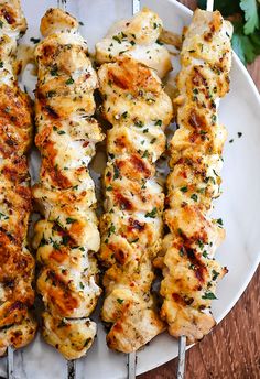 chicken skewers on a white plate with parsley