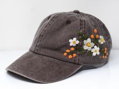 a baseball cap with flowers embroidered on the front and back side, sitting on a white surface