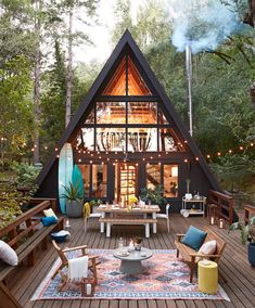 a wooden deck with furniture and lights in the middle, surrounded by greenery on both sides