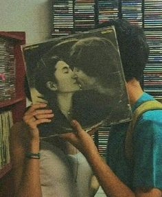 a man holding up a record in front of a woman's face and kissing her