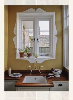 a kitchen sink sitting under a window with potted plants on the counter next to it