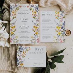 the wedding stationery is laid out with flowers and greenery