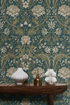 two white vases sitting on top of a wooden table next to a green wall