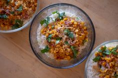 three bowls filled with rice and vegetables on top of a wooden table