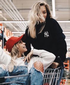 two women are sitting in a shopping cart