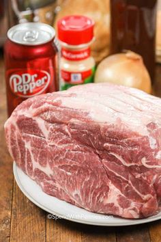 raw meat sitting on top of a white plate next to cans of soda and other ingredients