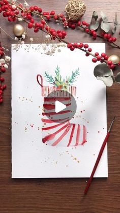 a christmas card with an ornament on it, surrounded by red berries and silverware