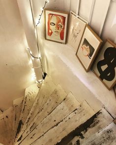 a staircase with pictures on the wall and framed artwork above it, along with lights