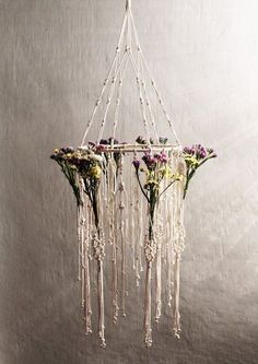 a chandelier with flowers hanging from it's sides in front of a wall