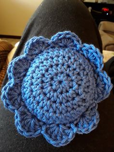 a blue crocheted flower sitting on top of a person's leg