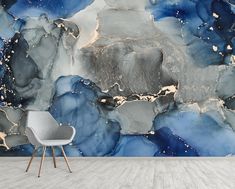 a chair sitting in front of a wall with blue and grey art work on it