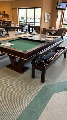 a pool table in the middle of a room with chairs around it and tables on either side