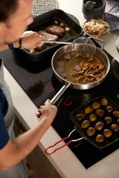 a man cooking food on top of a stove next to other pans filled with food