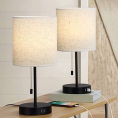 two lamps sitting on top of a wooden table next to a usb cable and plugged in