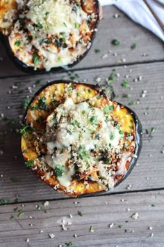 two stuffed acorns with cheese and herbs on the top are sitting on a wooden table