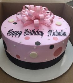 a pink birthday cake with polka dots and a bow