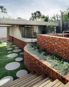 a brick house with green grass and white circles on the walkway leading up to it