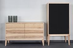 a black cabinet next to a wooden dresser with two vases sitting on top of it