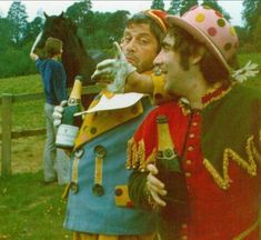 two men dressed as clowns standing next to each other in front of a horse