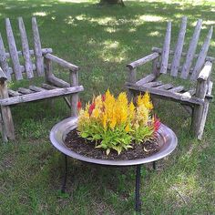 two wooden chairs sitting on top of a grass covered field next to a flower pot