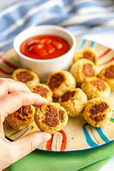 a person is holding up some food on a plate with dipping sauce in the background