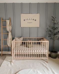 a baby's room with a crib, ladder and tree in the corner