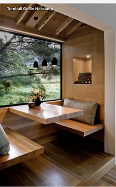 a wooden bench sitting under a window next to a table and chair in a room