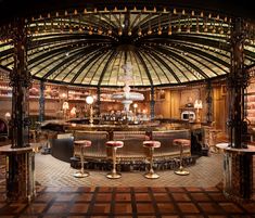 the inside of a bar with lots of tables and stools