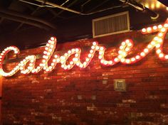 a brick wall with lights that spell out the word cashews on it's side