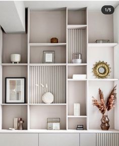 a white shelf filled with lots of books and vases on top of it's sides