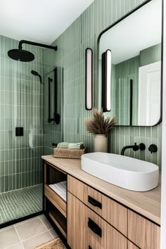 a bathroom with green tiled walls and flooring, including a large mirror over the sink