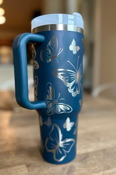 a blue travel mug with butterflies on it