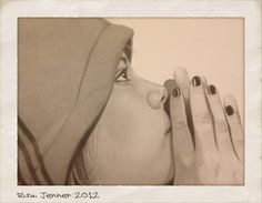 a woman with black and white nails holding her face up to the side while wearing a hoodie