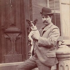 an old photo of a man holding a small dog