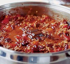 a pot filled with chili and meat sitting on top of a stove