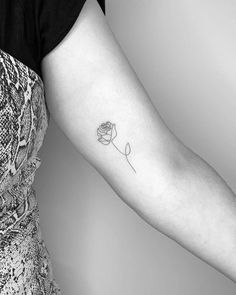 a woman's arm with a single rose tattoo on the left side of her arm