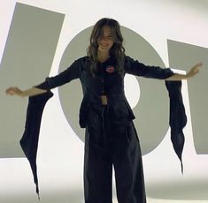 a woman standing in front of a large sign with her arms spread out to the side