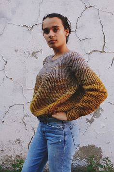 a woman standing in front of a white wall with her hands on her hips and looking at the camera