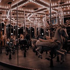 an old fashioned carousel with horses and people riding on the merry go round at night