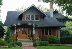 a gray house with red shutters on the front door and steps leading up to it