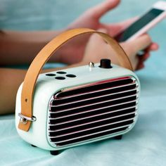 an old fashioned radio sitting on top of a bed next to a person holding a cell phone