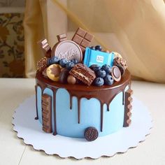 a cake with chocolate, blueberries, and other sweets on it sitting on a table