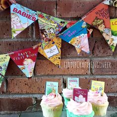 there are cupcakes with pink frosting on them and some books hanging from the wall