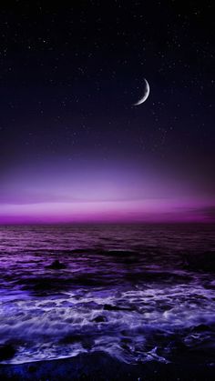 the moon is shining in the sky above the ocean and water at night time with purple hues