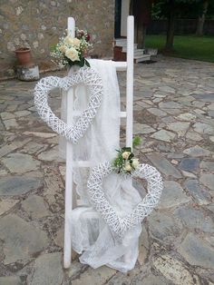 a white chair with two flowers on it sitting in the middle of a stone walkway