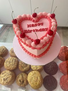 a heart shaped cake surrounded by cookies and muffins